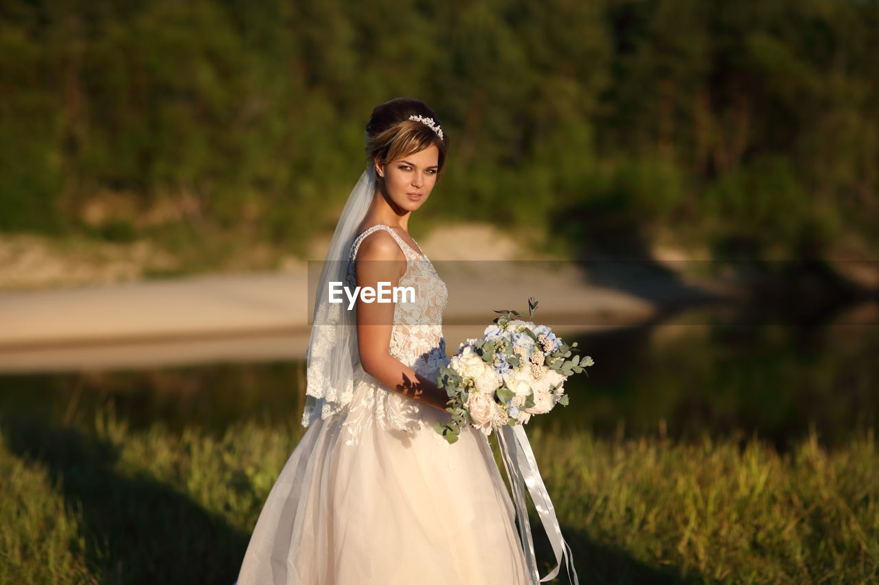 Bride with a bouquet of flowers on the background of the river
