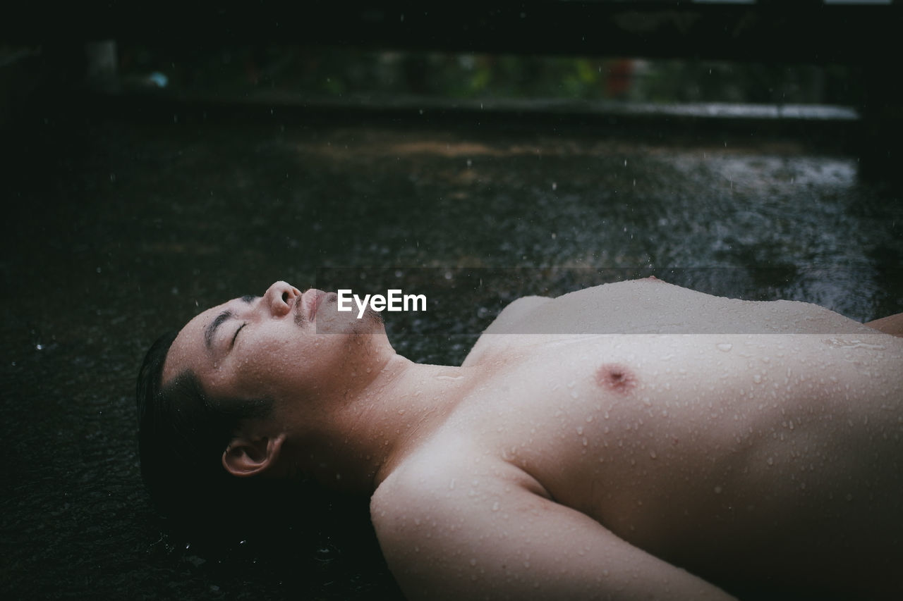 Side view of shirtless man lying in water