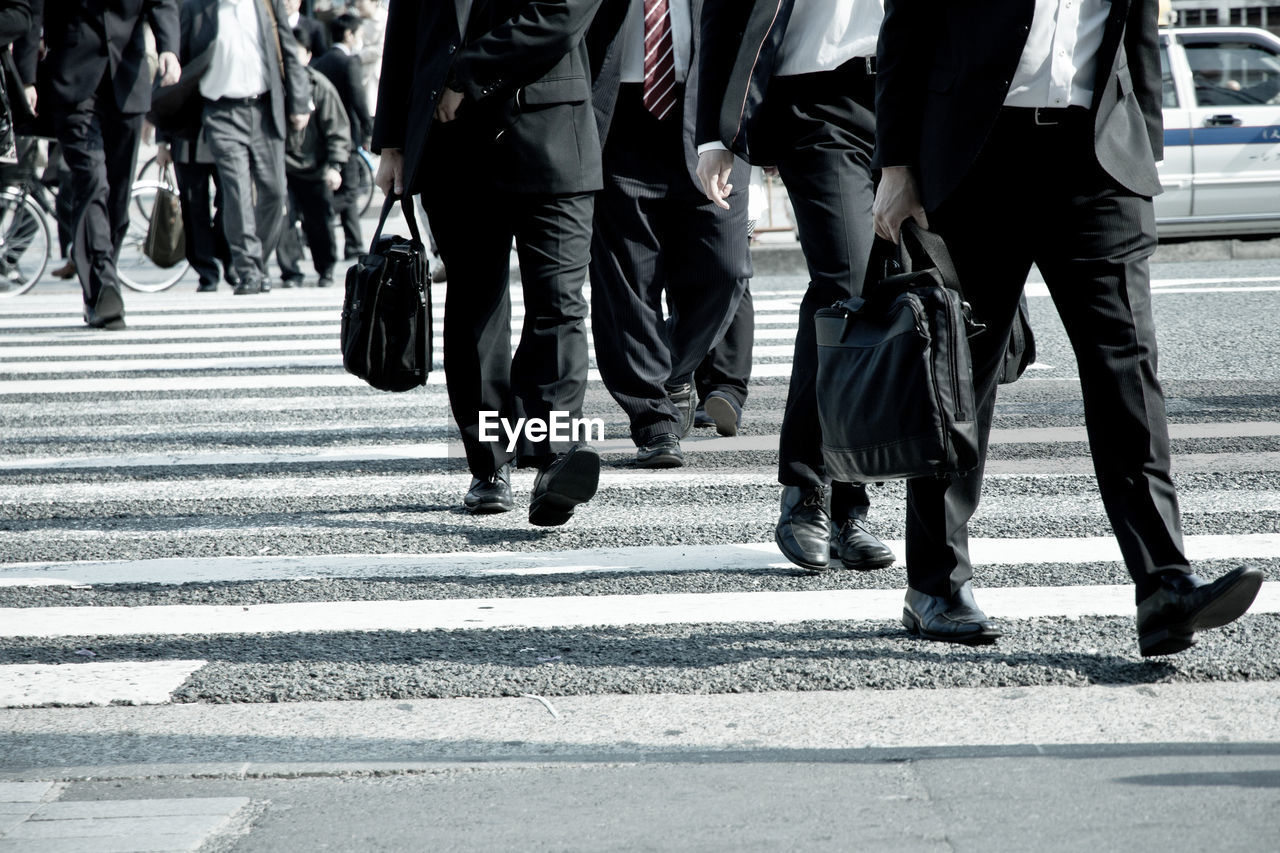 Low section of business people walking on road