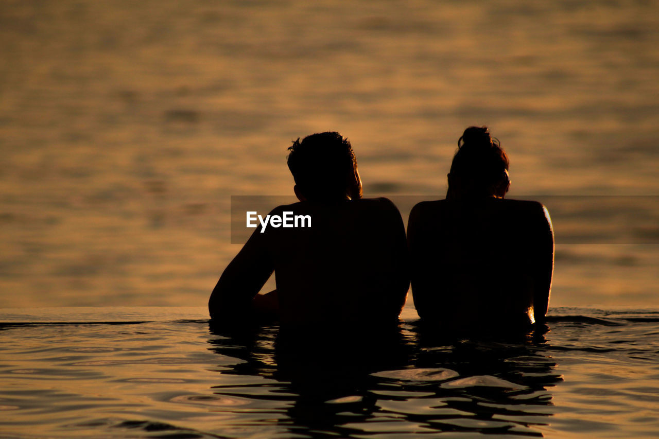 couple, talking in the swimming pool, looking at the sea