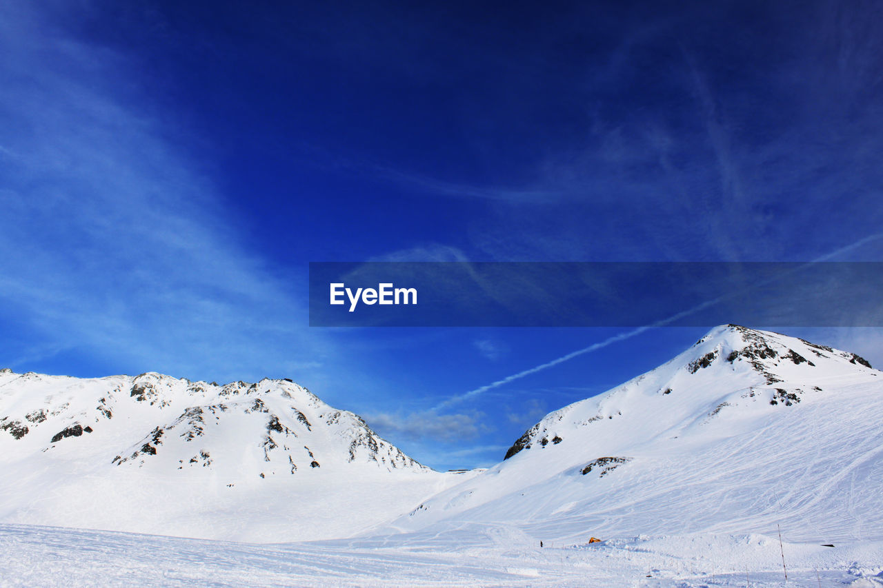 Scenic view of snow covered mountains against blue sky