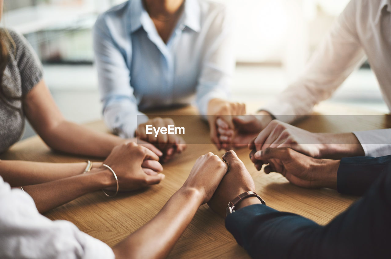 midsection of business colleagues stacking hands