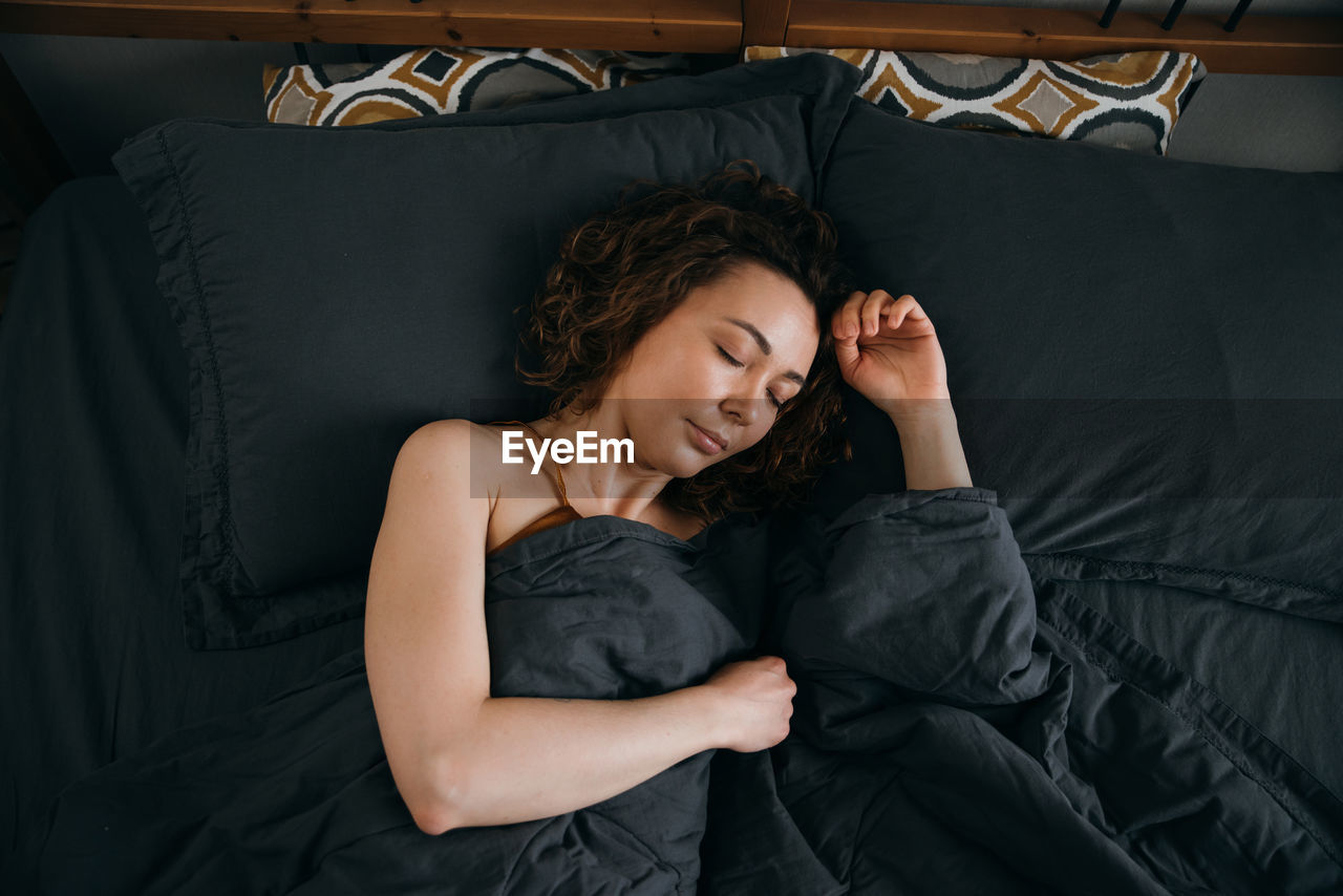 Beautiful young woman sleeps in bed in the early morning