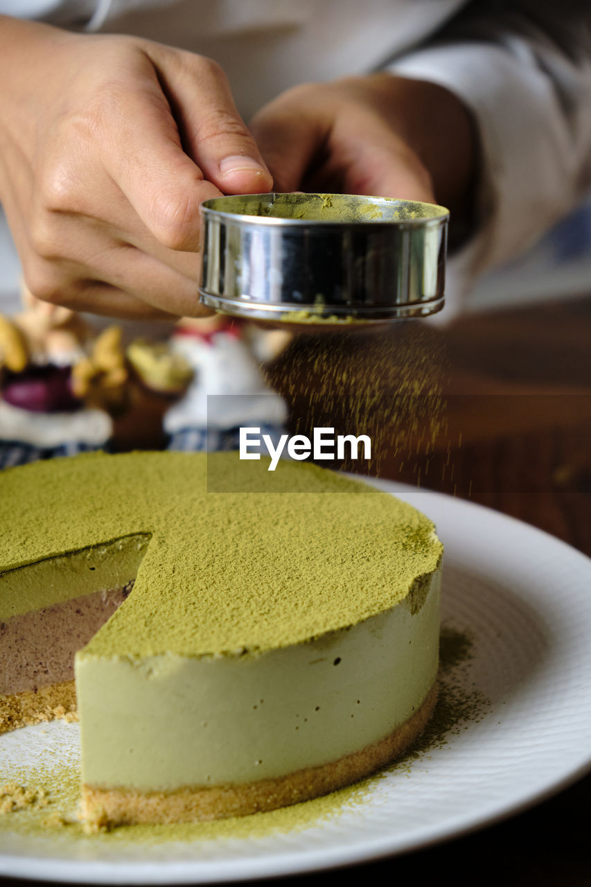 CLOSE-UP OF PERSON PREPARING FOOD IN CUP