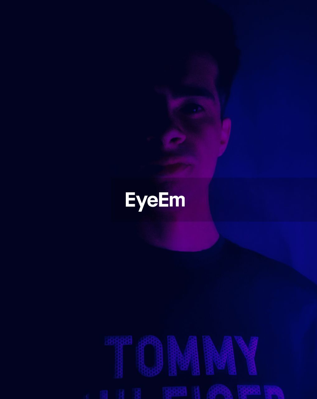 one person, studio shot, portrait, blue, young adult, indoors, adult, front view, purple, darkness, headshot, dark, communication, person, text, human face, black background, font, copy space, men, looking at camera