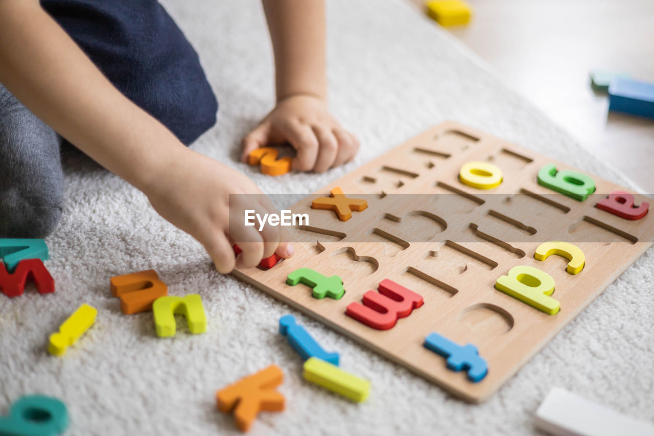 midsection of woman playing with toy blocks on table