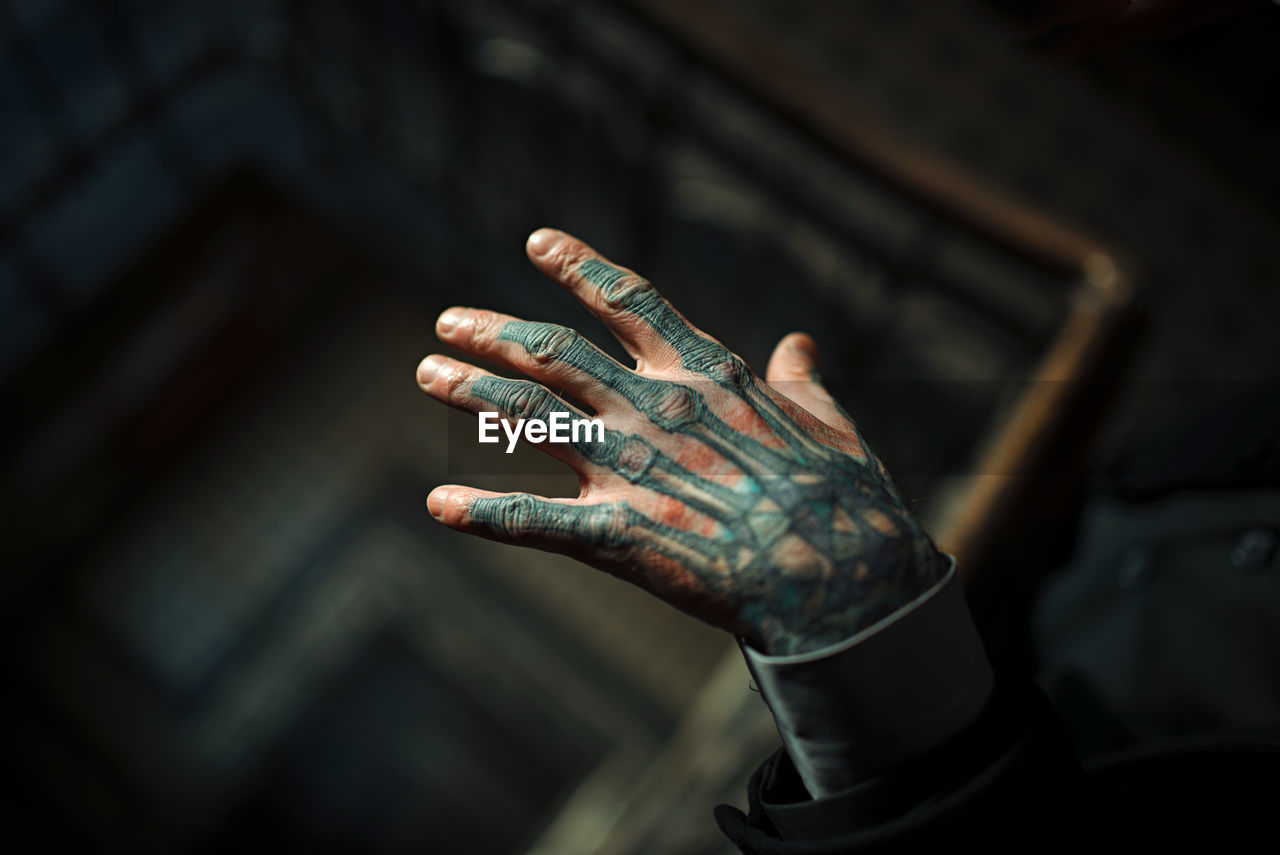 Cropped hand of young man with tattoo over spiral staircase