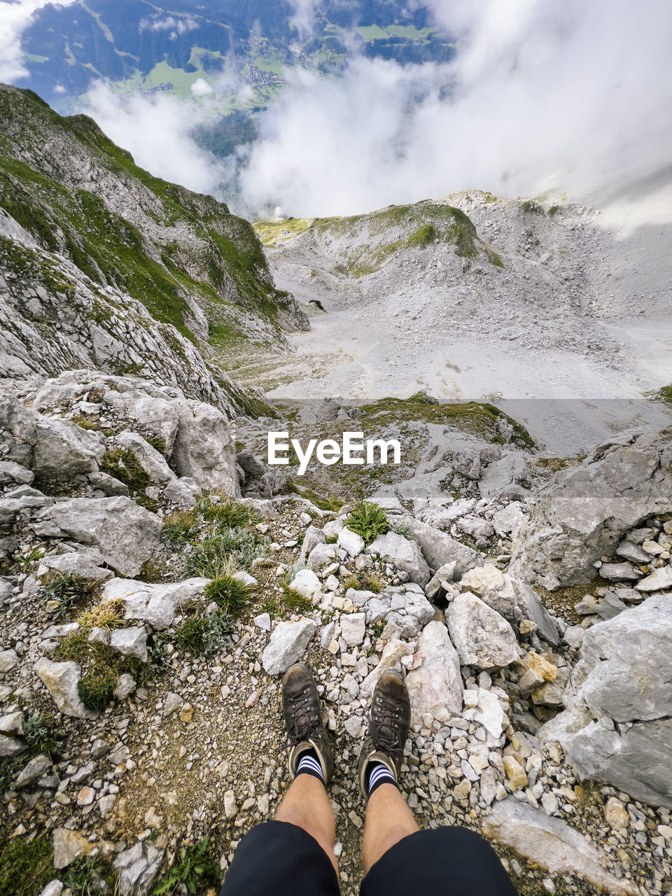 low section, one person, human leg, leisure activity, personal perspective, mountain, nature, walking, shoe, adventure, environment, scenics - nature, beauty in nature, lifestyles, landscape, mountain range, cloud, hiking, rock, activity, sky, wilderness, land, travel, day, adult, limb, outdoors, water, human limb, human foot, standing, travel destinations, sports, non-urban scene, footwear, exploration, ridge, men, holiday, vacation, recreation, trip, geology, tranquility