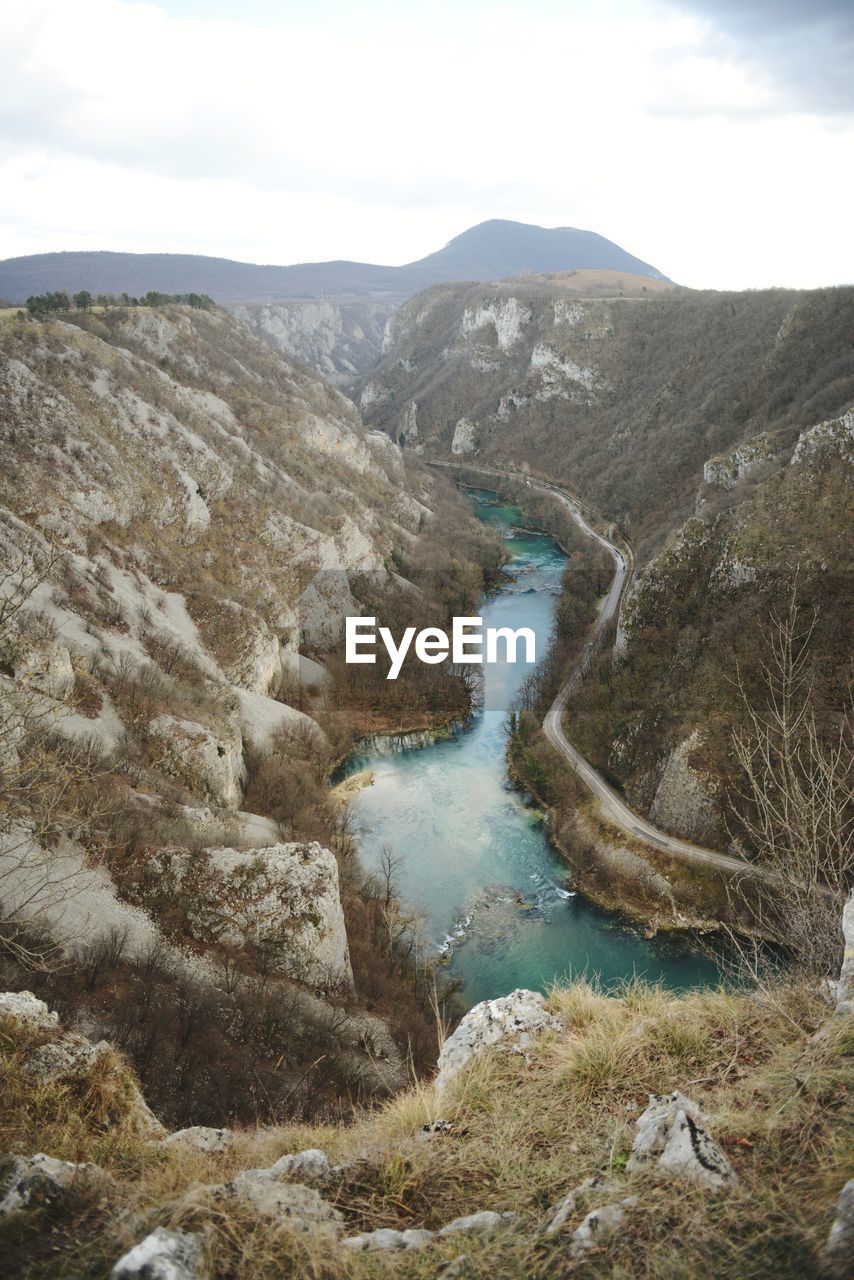 HIGH ANGLE VIEW OF RIVER FLOWING THROUGH MOUNTAINS