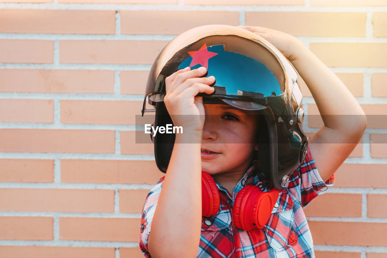 Portrait of boy with russian pilot's helmet on brick wall