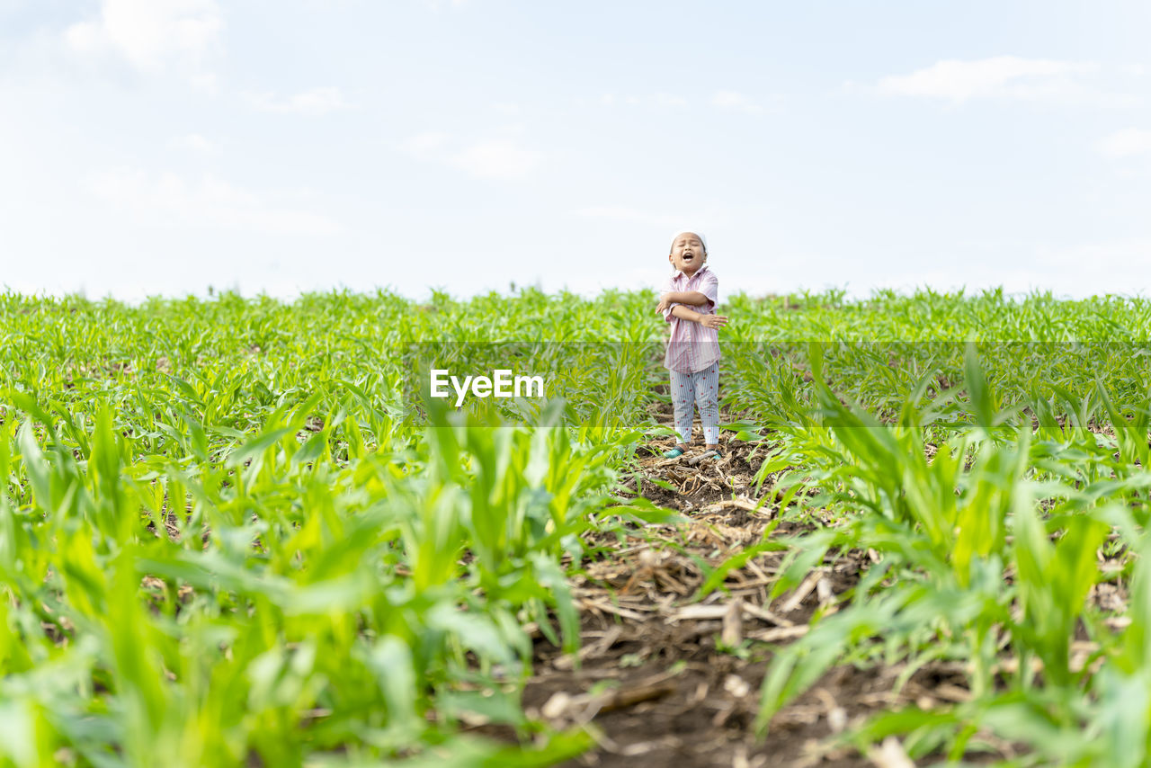 Full length of boy standing at farm against sky