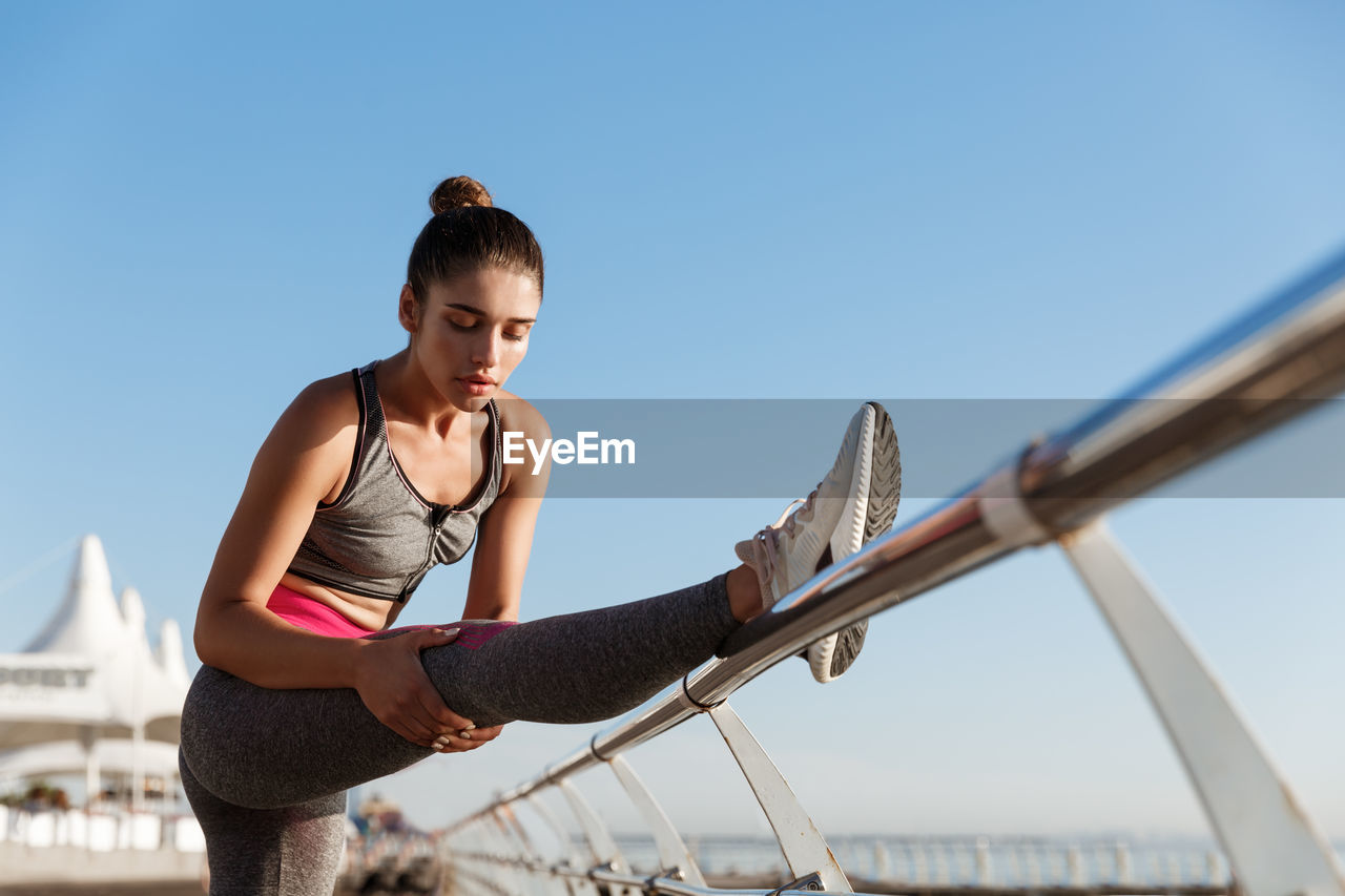 Young woman looking at camera against clear sky