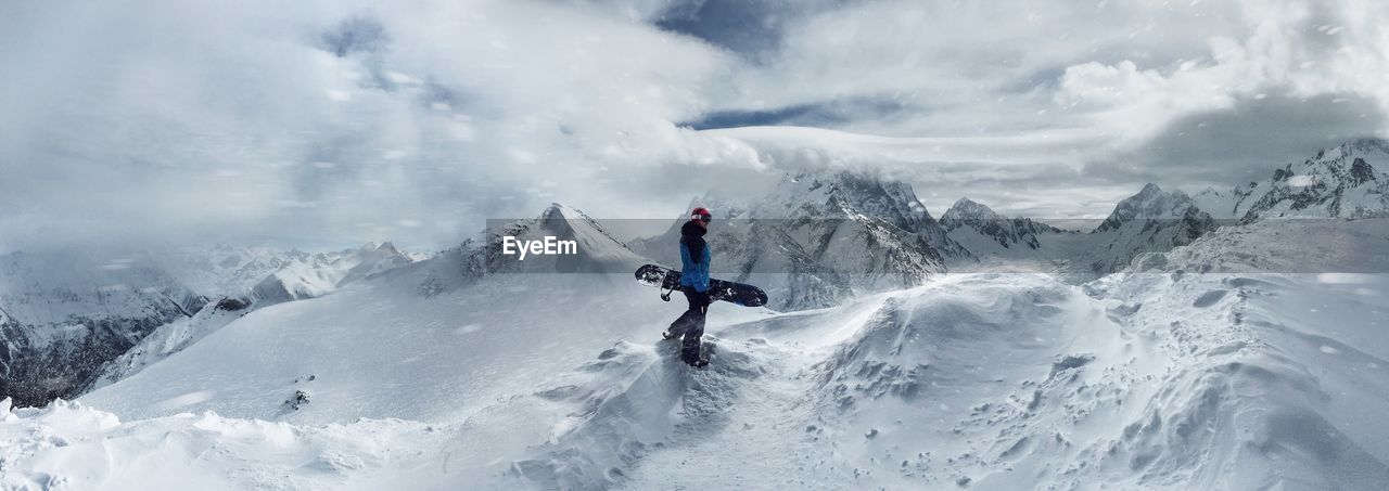 Side view of man walking on snowcapped mountains against sky