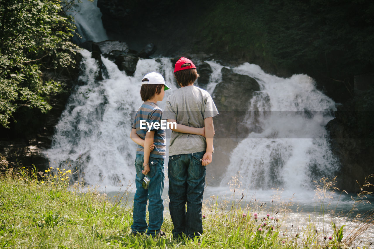 Rear view of boys waterfall in stream