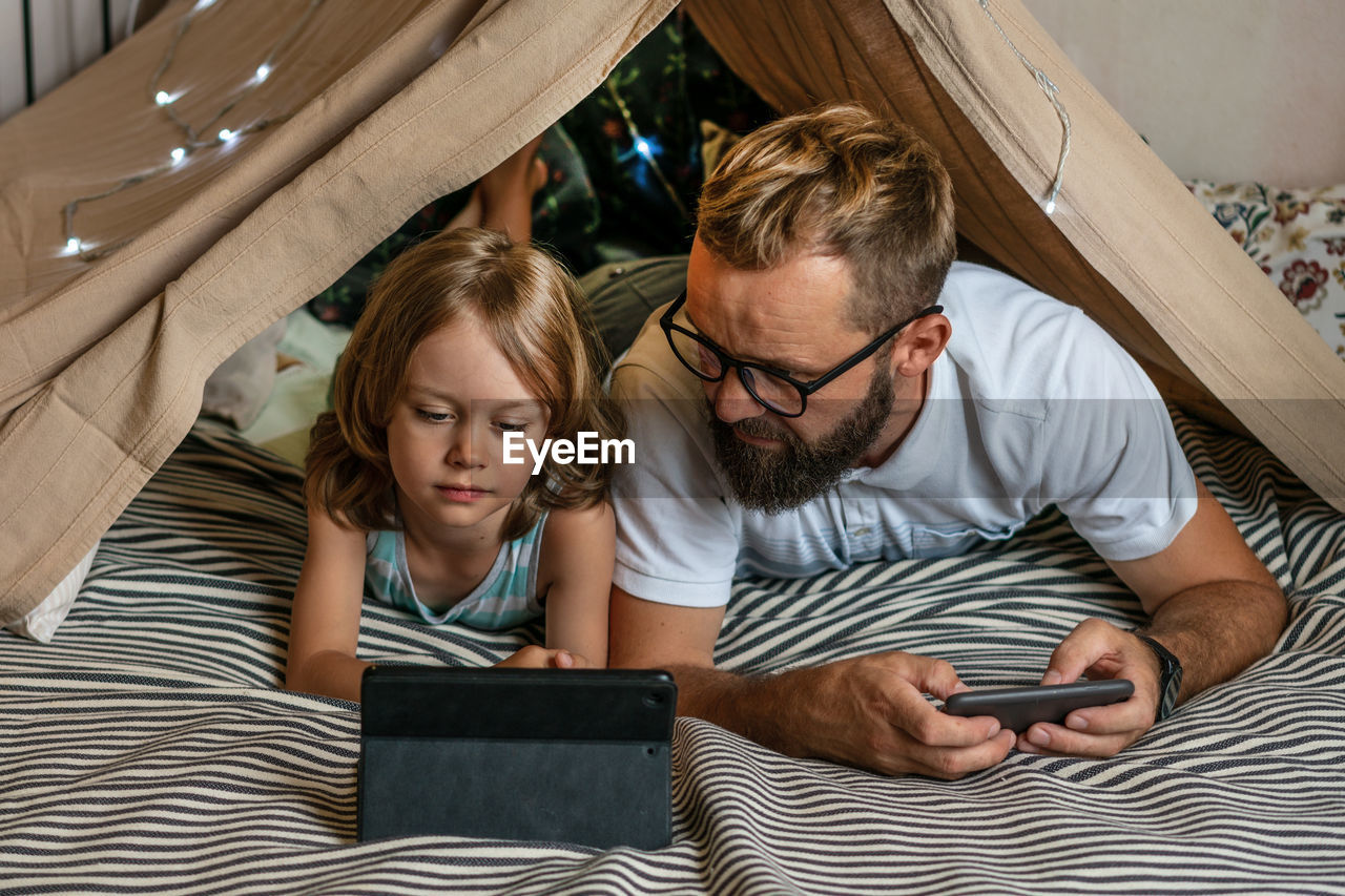 Father and son playing in a teepee tent at home.