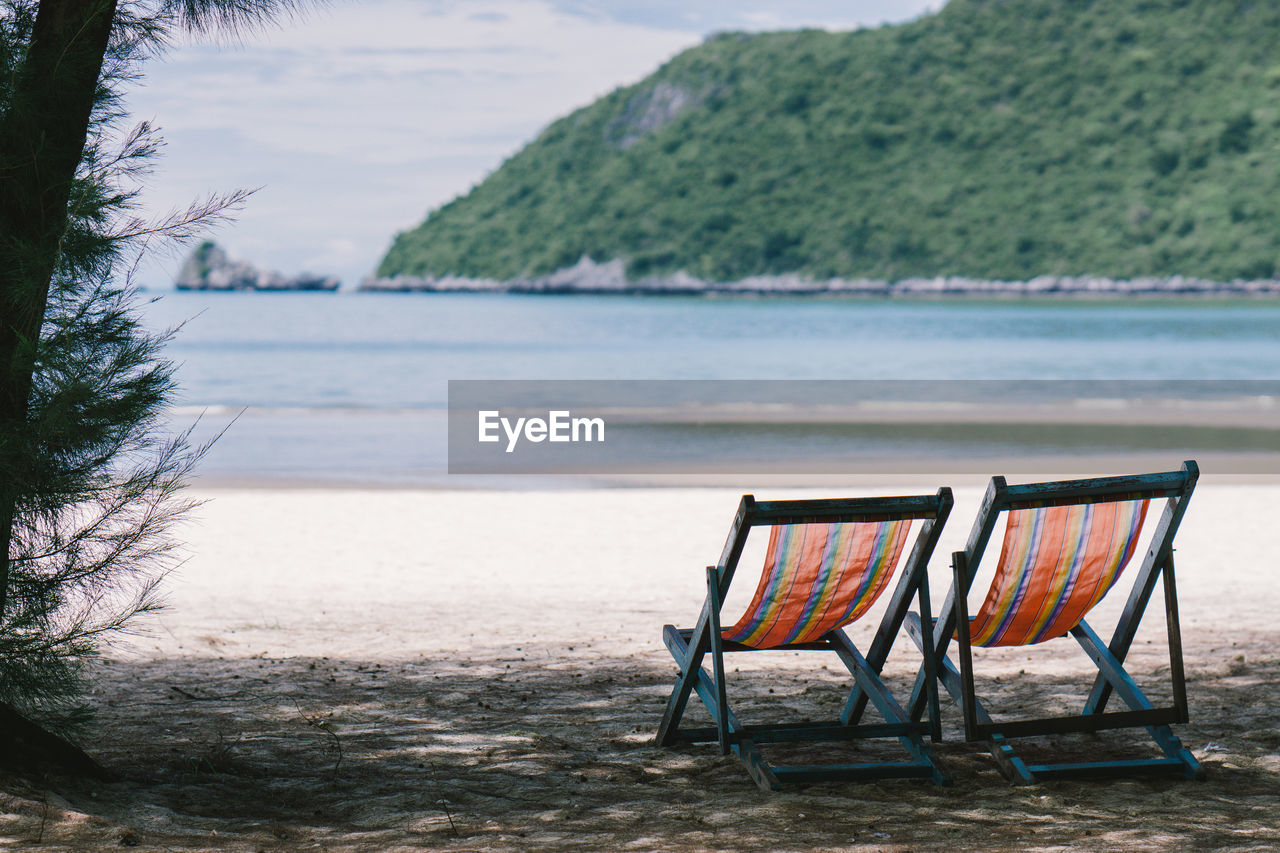 Chairs on beach against mountain