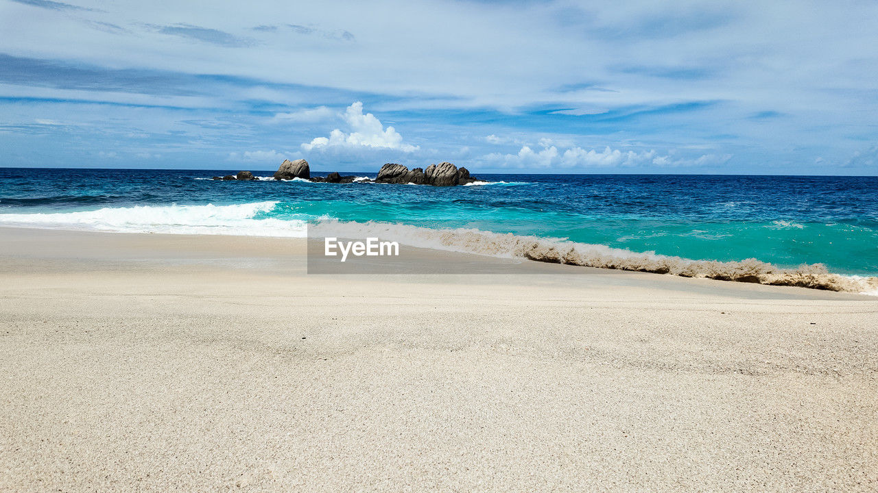 sea, land, water, beach, sky, scenics - nature, sand, beauty in nature, body of water, cloud, ocean, shore, wind wave, wave, nature, horizon, travel, travel destinations, horizon over water, tranquility, tranquil scene, coast, motion, holiday, environment, trip, vacation, coastline, blue, water's edge, tourism, idyllic, landscape, no people, tropical climate, day, outdoors, island, seascape, sports, water sports, summer, non-urban scene, nautical vessel, bay, turquoise colored