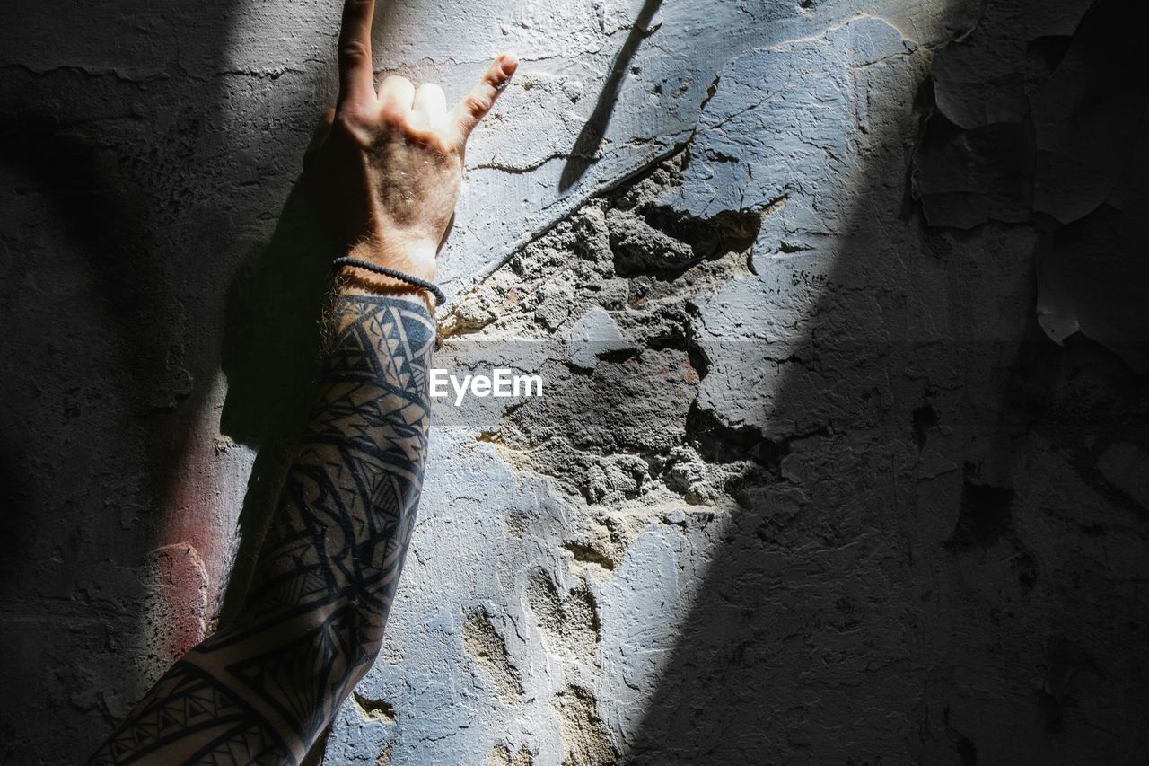 Cropped image of tattooed hand on broken wall