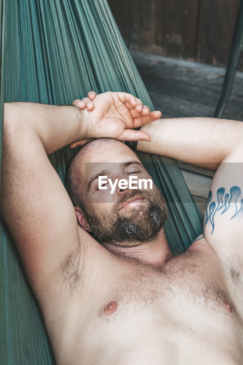 High angle view of portrait of man lying on hammock