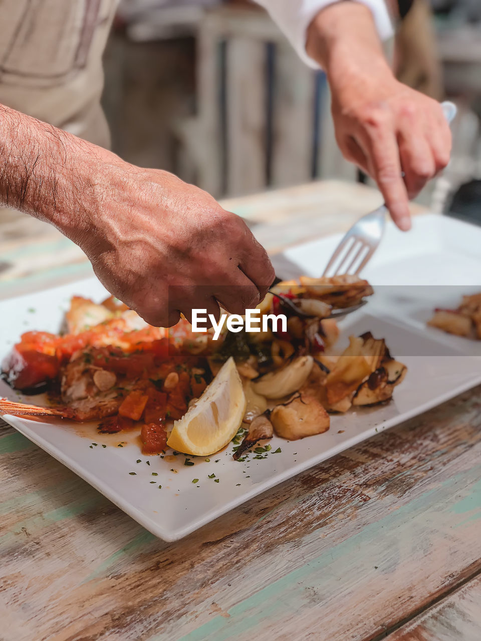 Cropped hands of man eating food on table