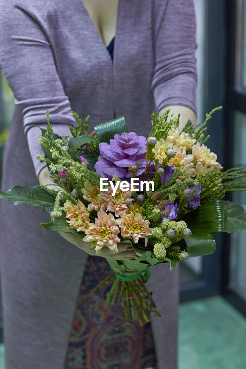 Midsection of woman holding bouquet