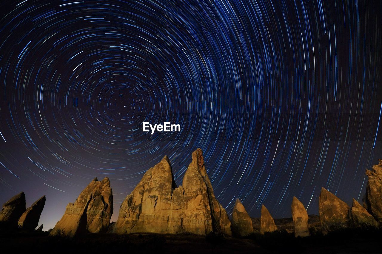 Low angle view of mountains against star trail at night