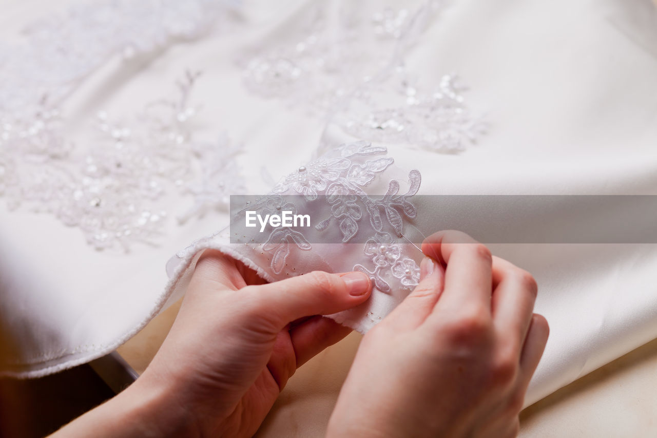 Cropped hands of woman stitching wedding dress