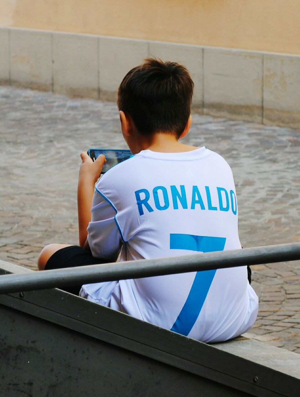 REAR VIEW OF BOY SITTING ON SEAT