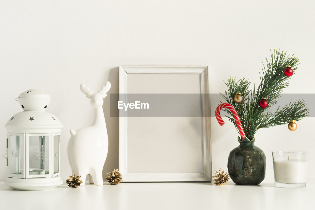 White composition with little christmas tree in vase, deer and candles. front view mockup template.