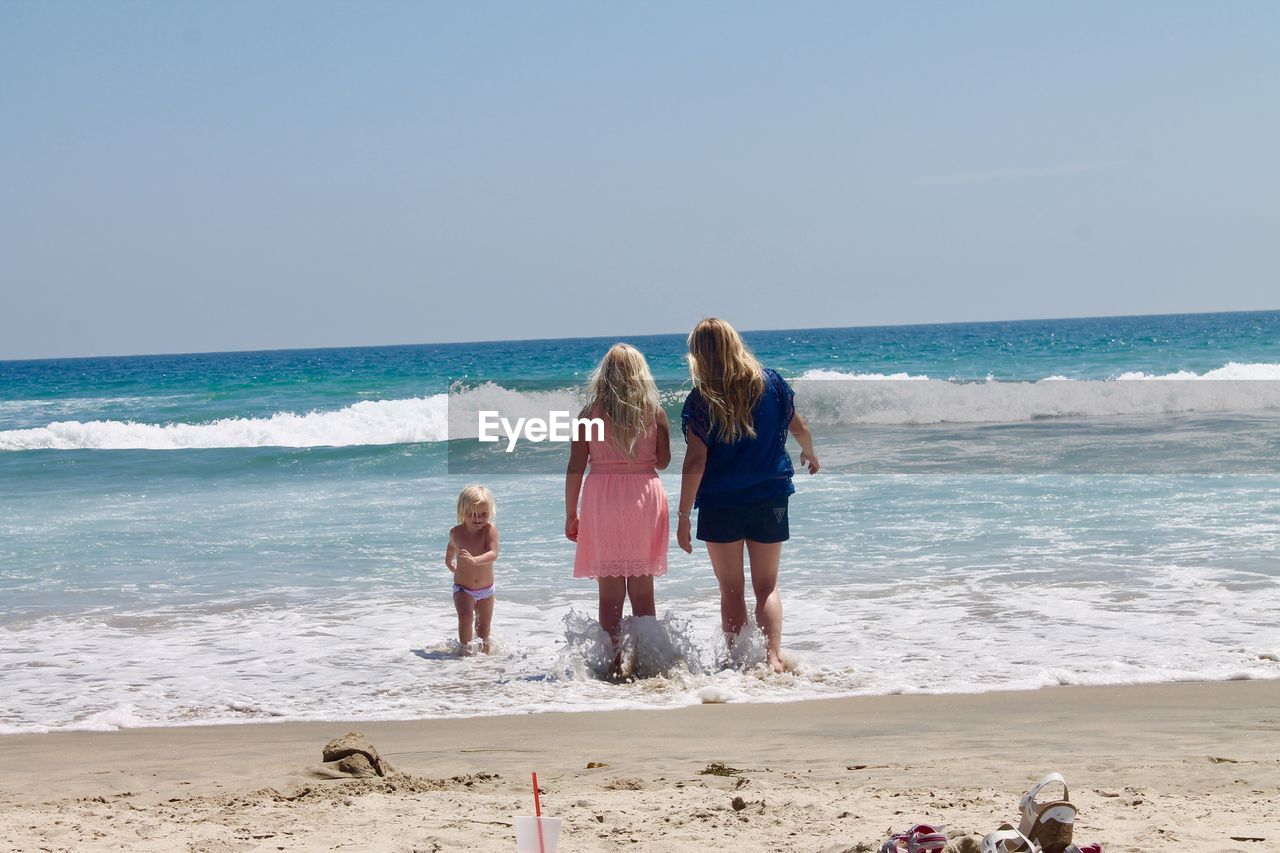 Family walking at beach against sky