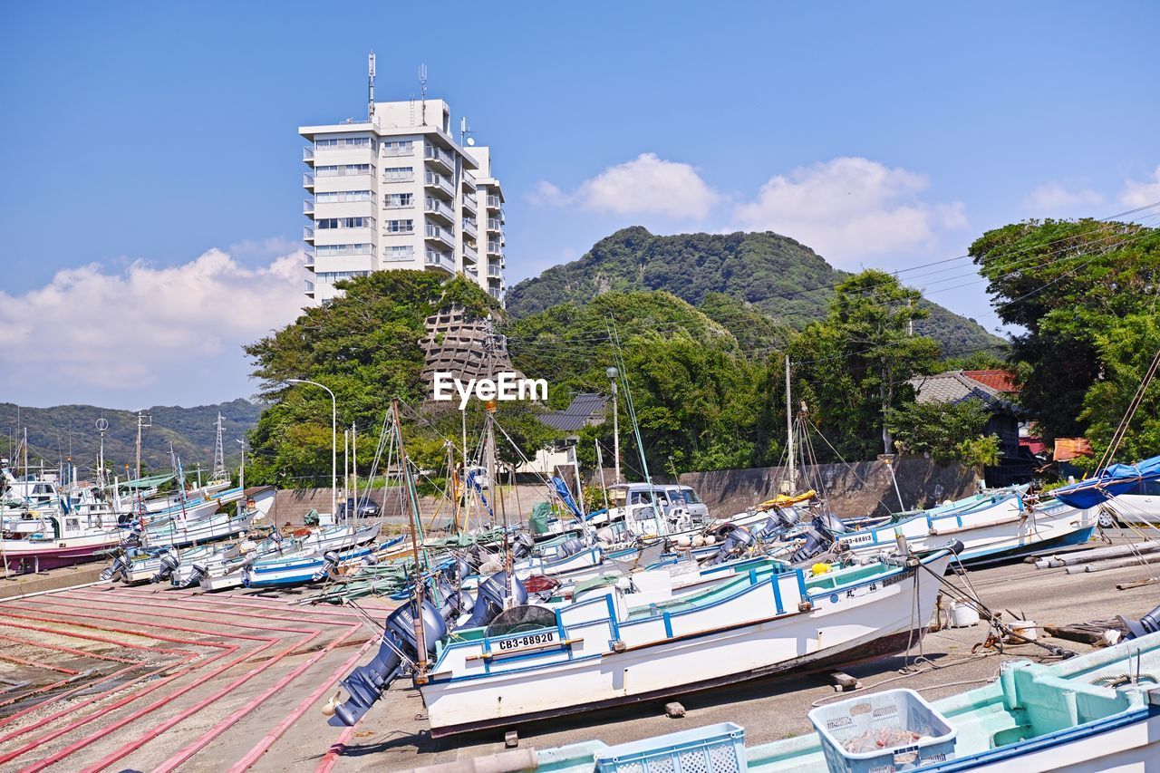 Boats moored at harbor by sea against sky