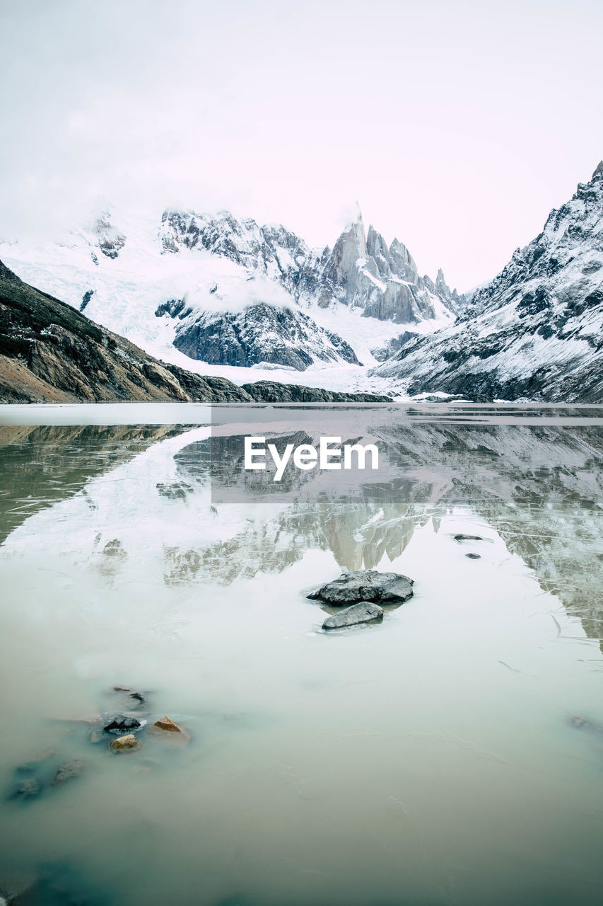 Glacial lake with snowcapped mountains in the background in winter