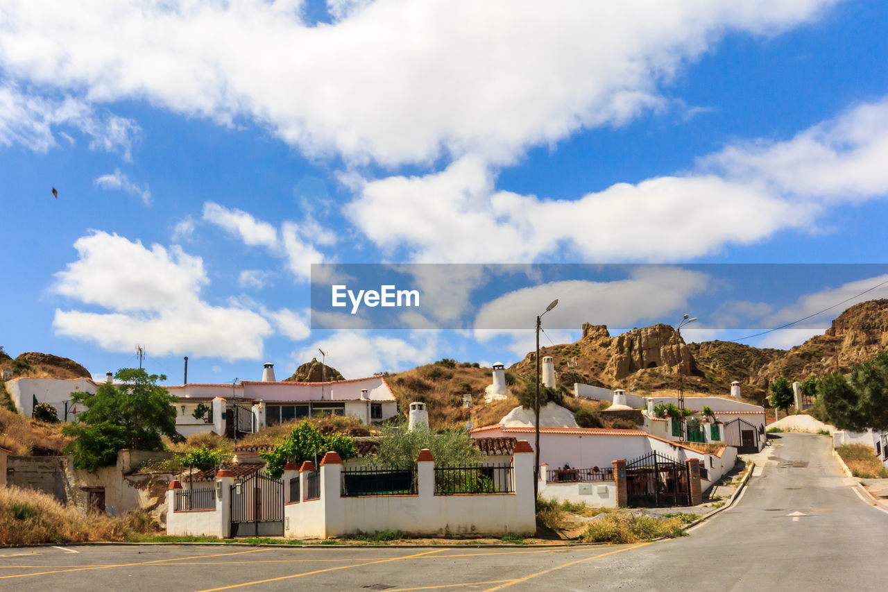 HOUSES BY ROAD AGAINST BUILDINGS IN CITY