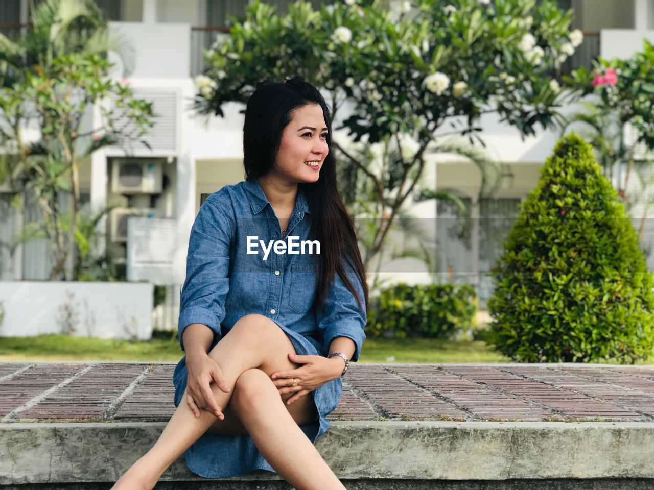 Smiling woman sitting on footpath