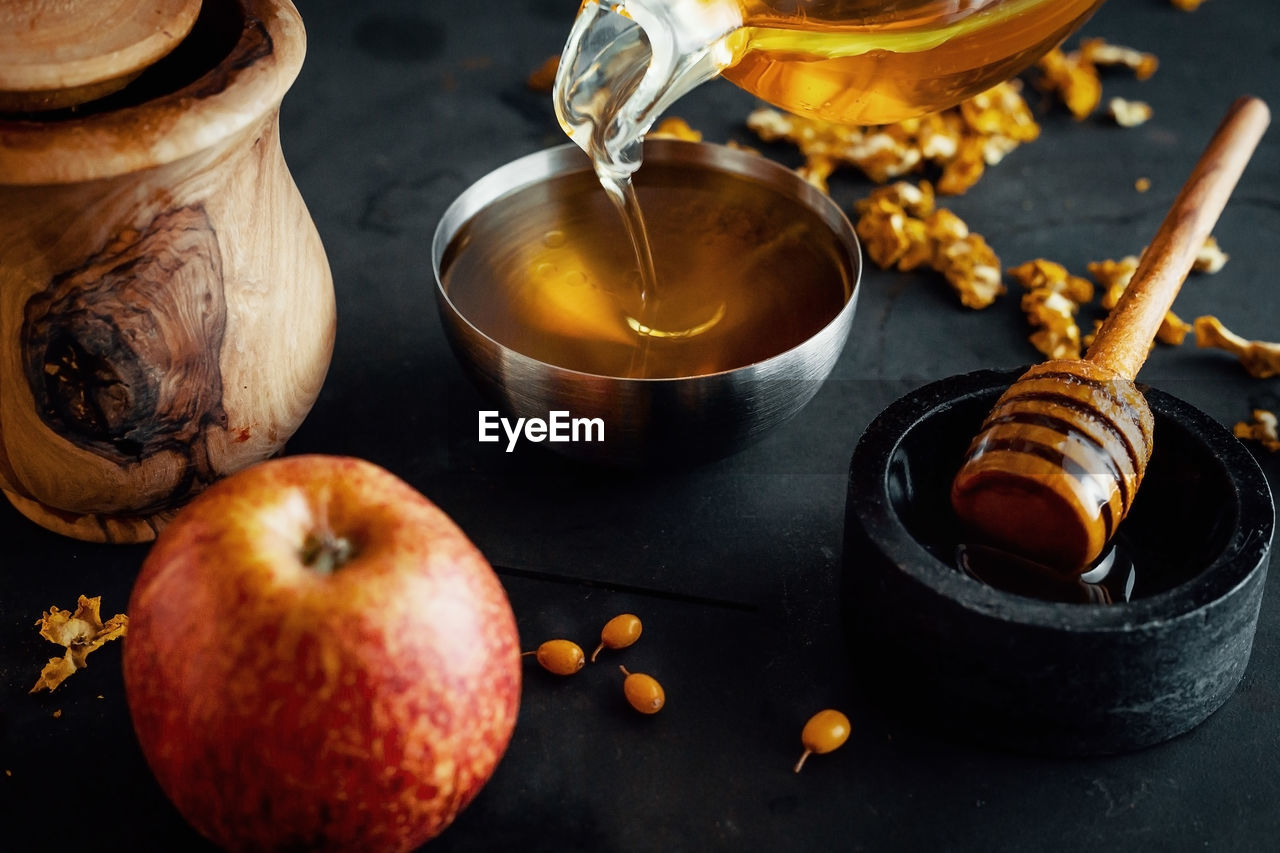 Natural honey is poured into a bowl, decorated with fruit and flowers