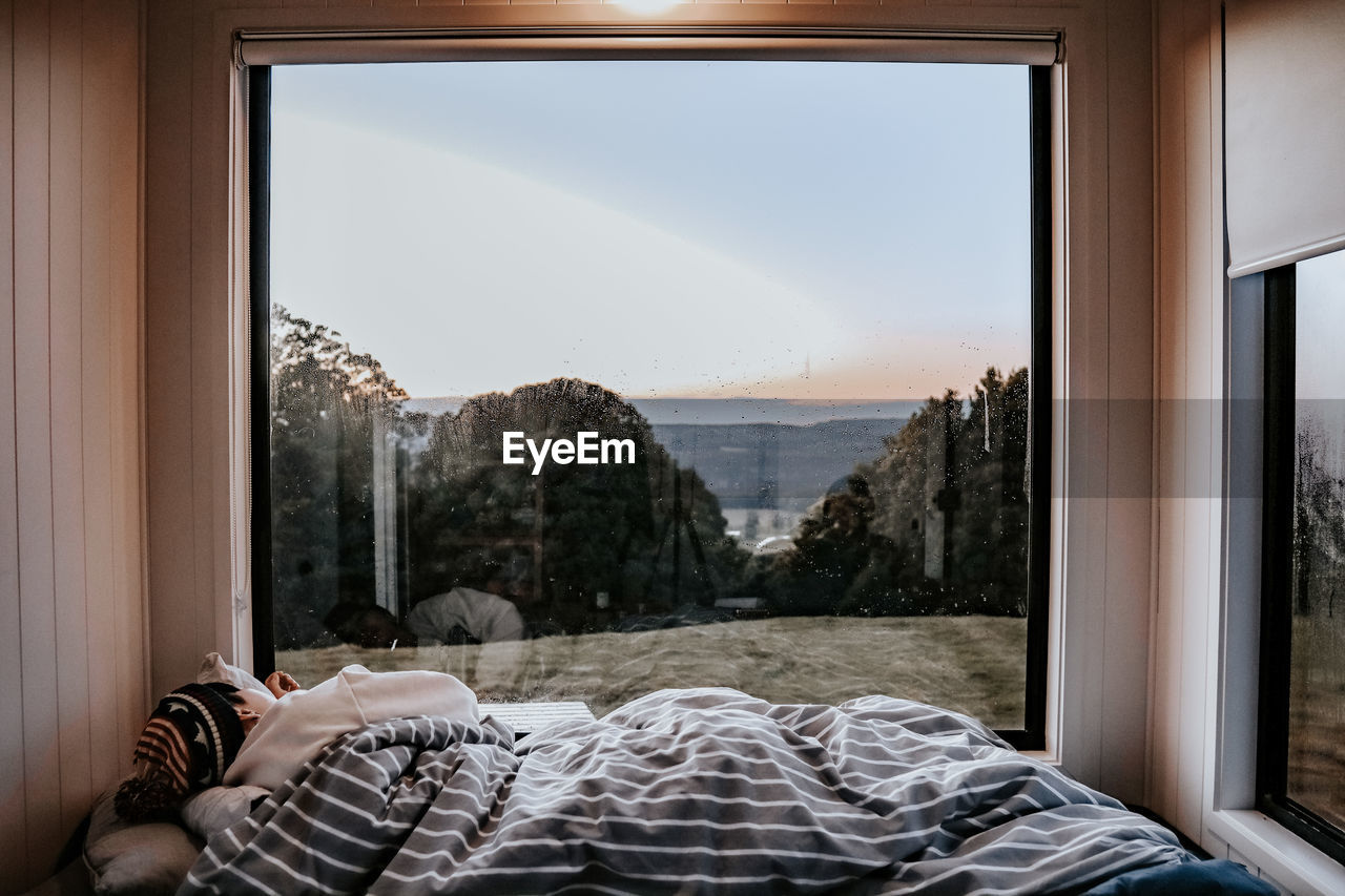 Rear view of woman sleeping on bed against landscape