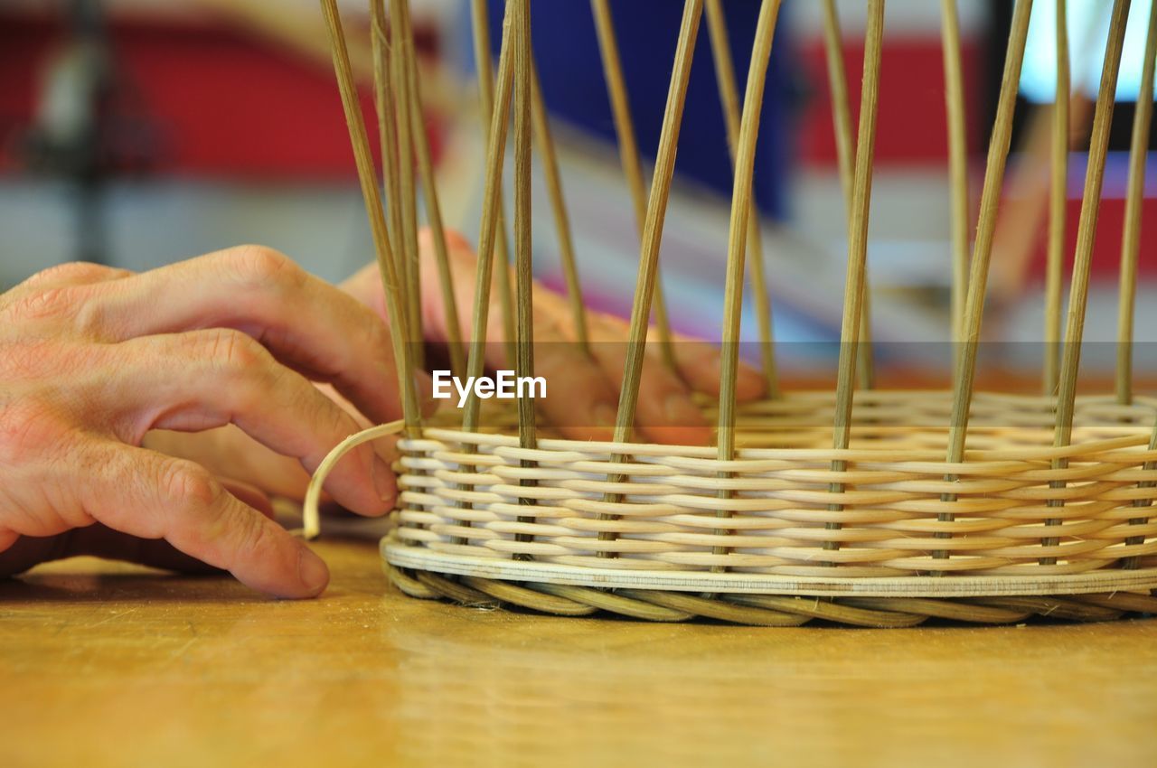 Cropped hands making wicker basket