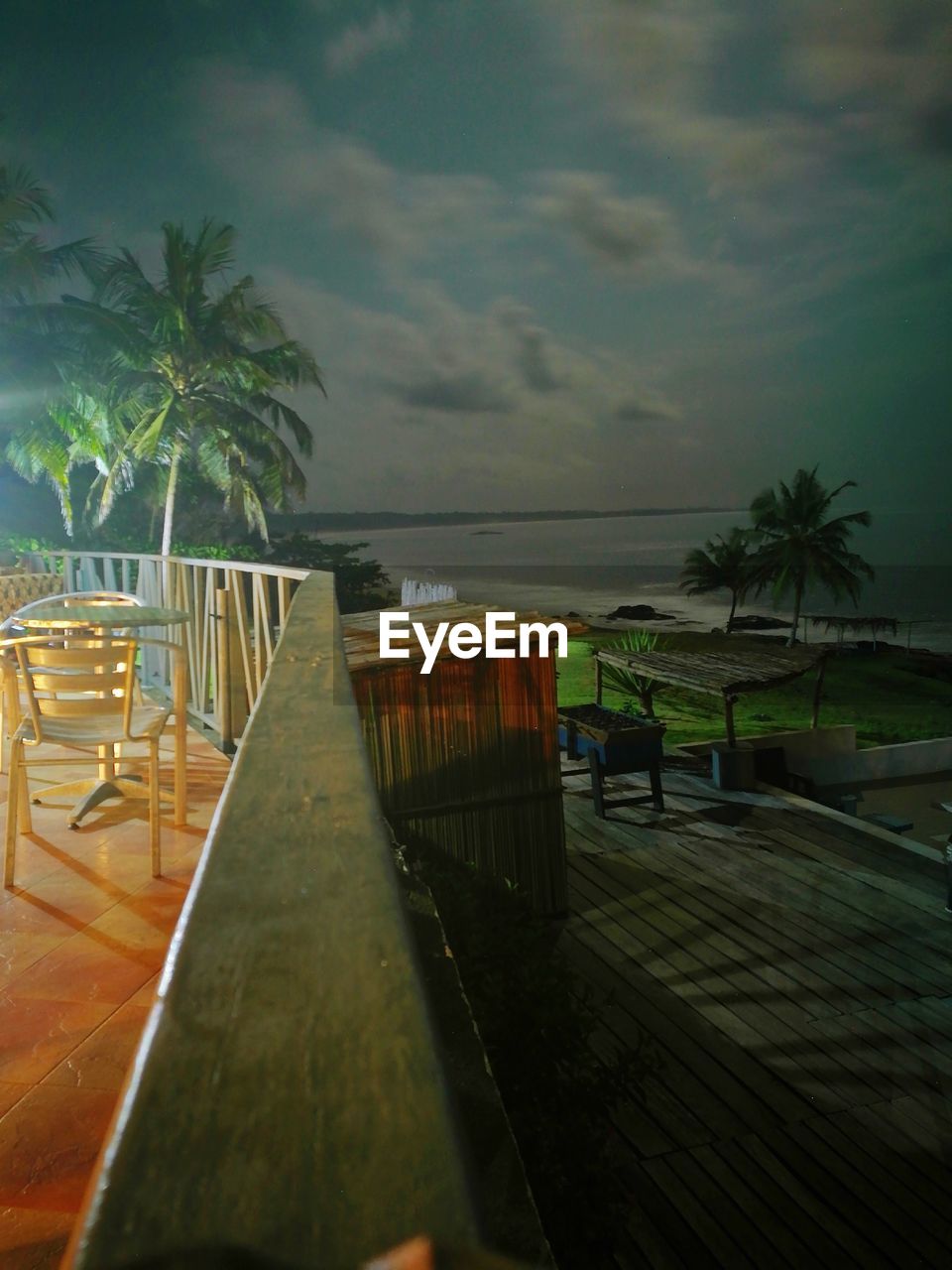 CHAIRS AND TABLE BY SWIMMING POOL AGAINST SEA