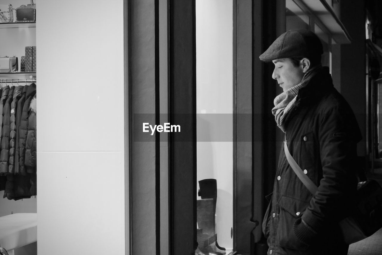 Side view of man standing by window