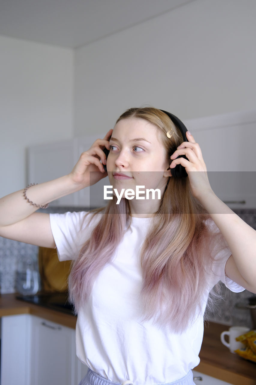 A cute caucasian teen girl listening music with wireless headphones