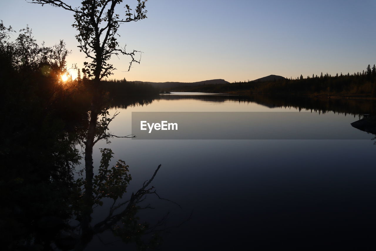 SCENIC VIEW OF LAKE AGAINST CLEAR SKY AT SUNSET