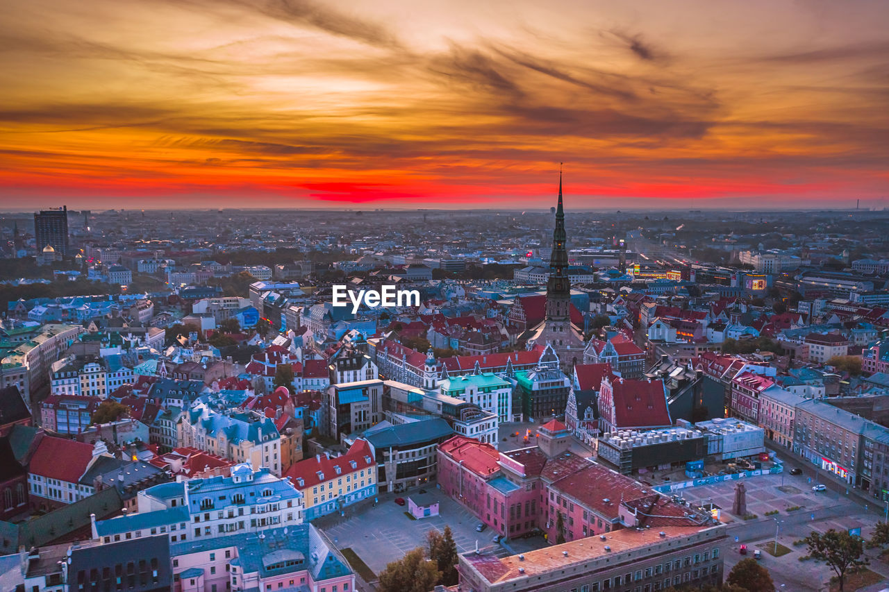 HIGH ANGLE VIEW OF CITY AGAINST CLOUDY SKY AT SUNSET