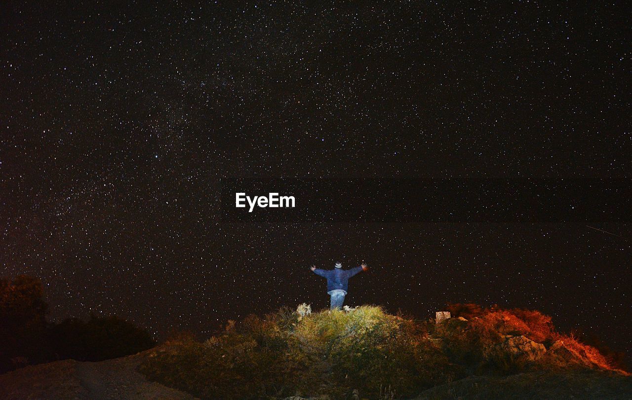 Low angle view of man standing against star field at night