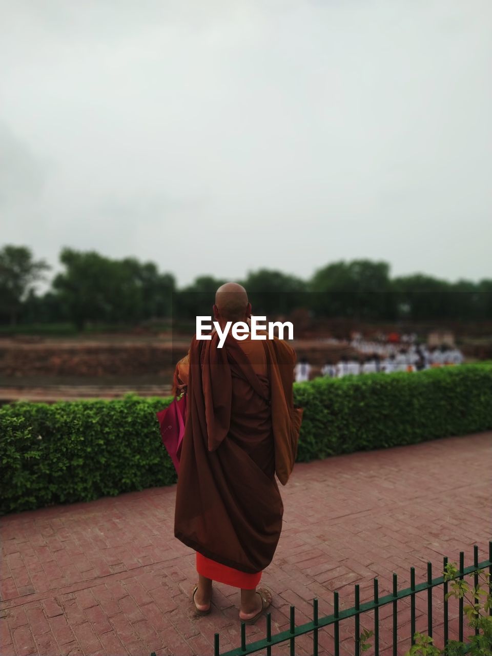 Rear view of monk wearing traditional clothing standing on footpath