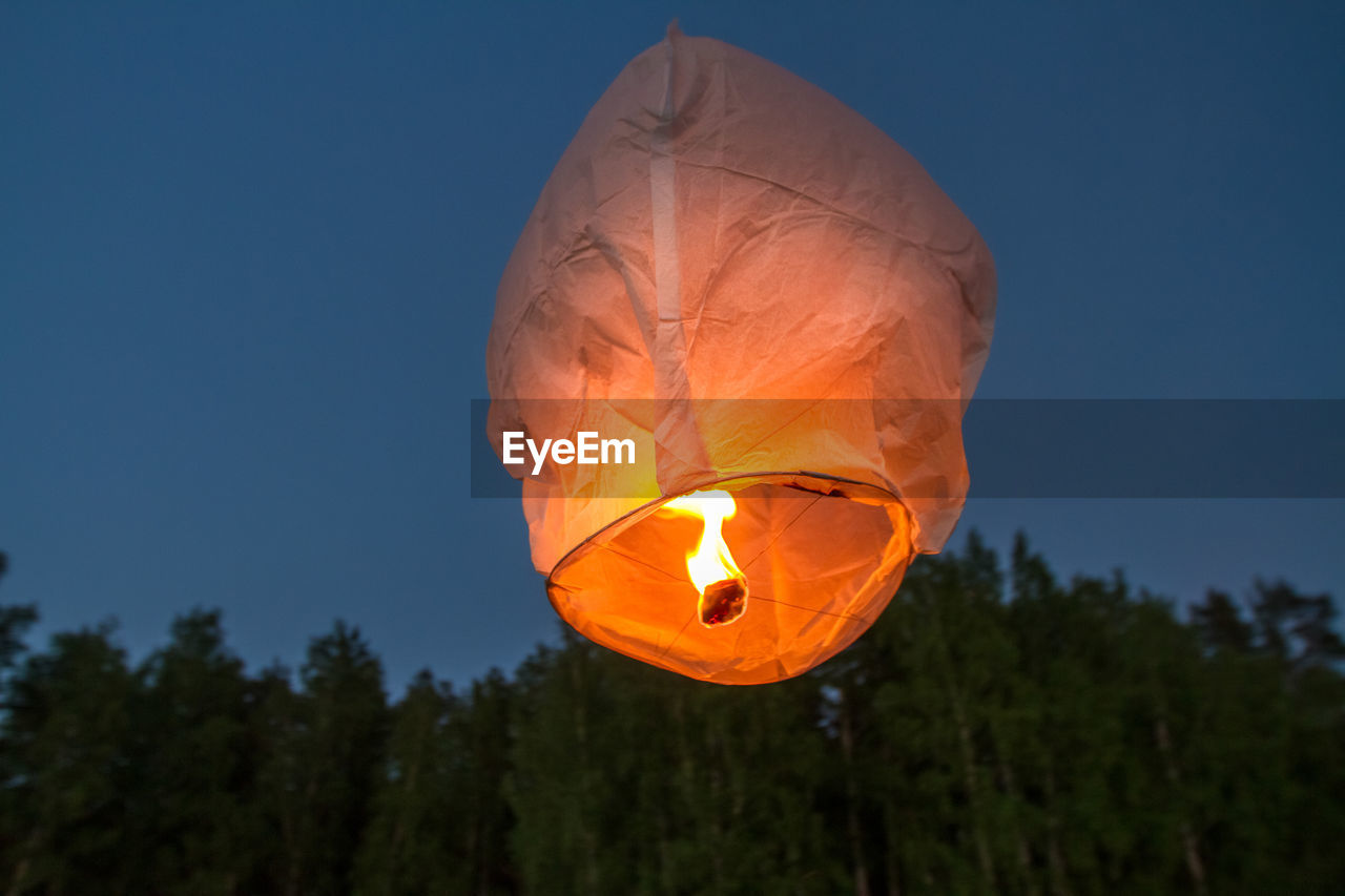 Low angle view of paper lantern flying against clear sky