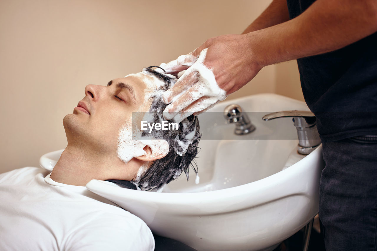 midsection of man washing hands in bathroom