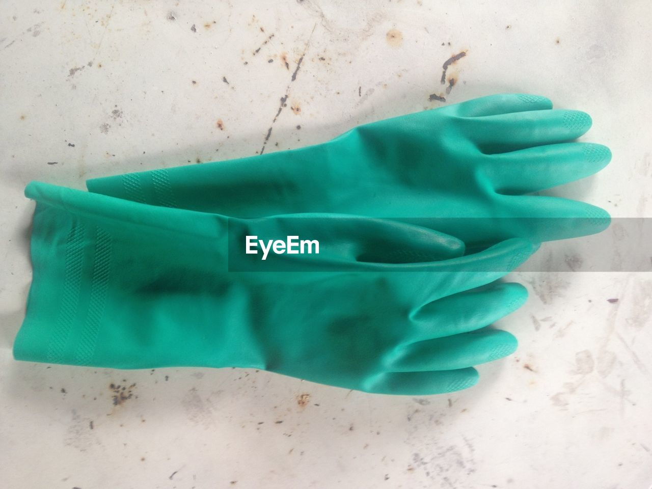 Pair of green washing up gloves on floor