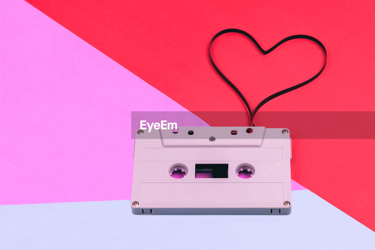 Close-up of audio cassette reel making heart shape over colored background