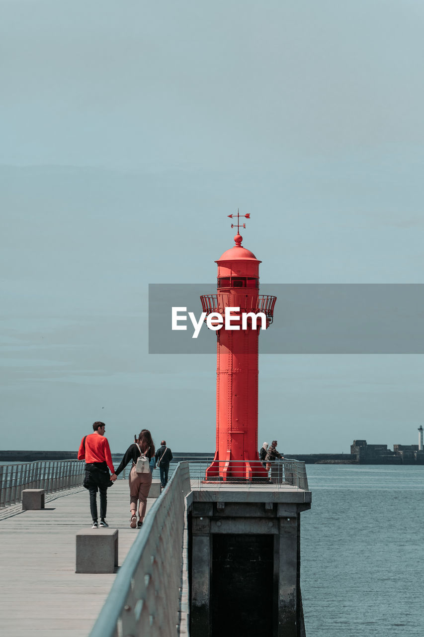 Couple walking on pier against sky