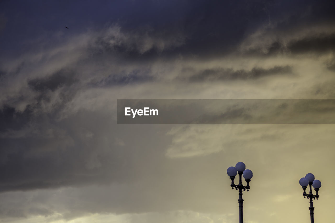 Low angle view of street lights against cloudy sky during sunset